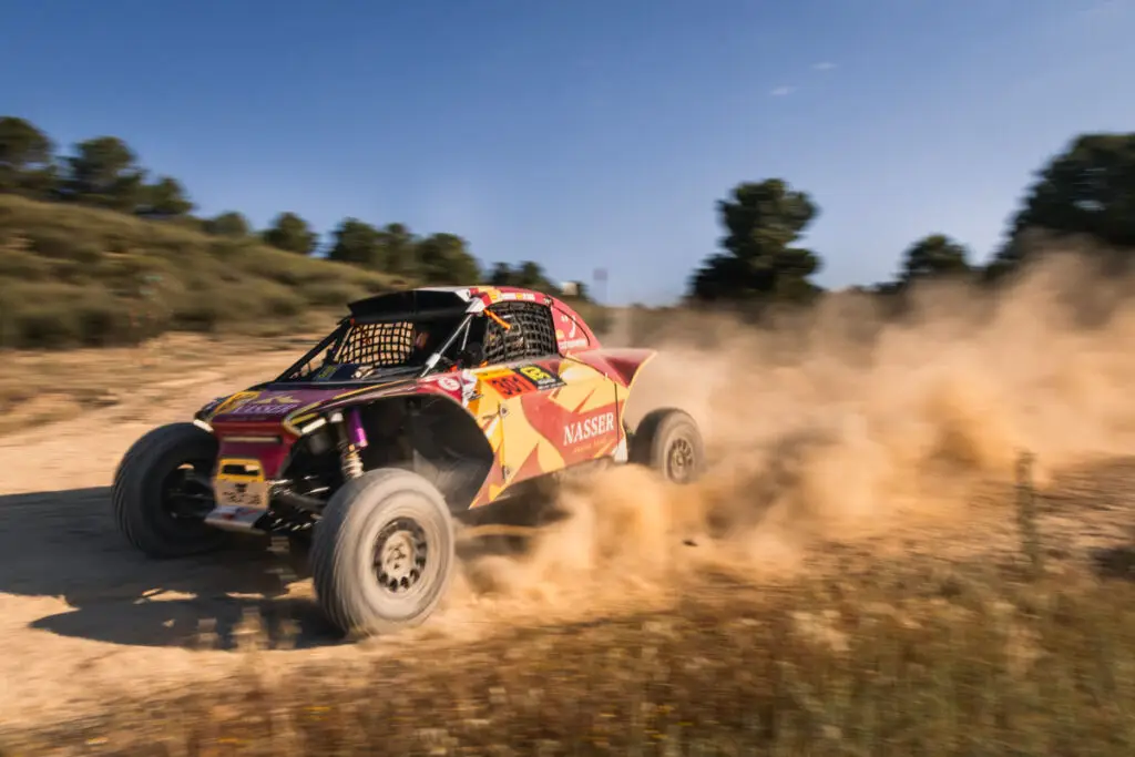 Coche del equipo Nasser tomando una curva a fondo en rally raid
