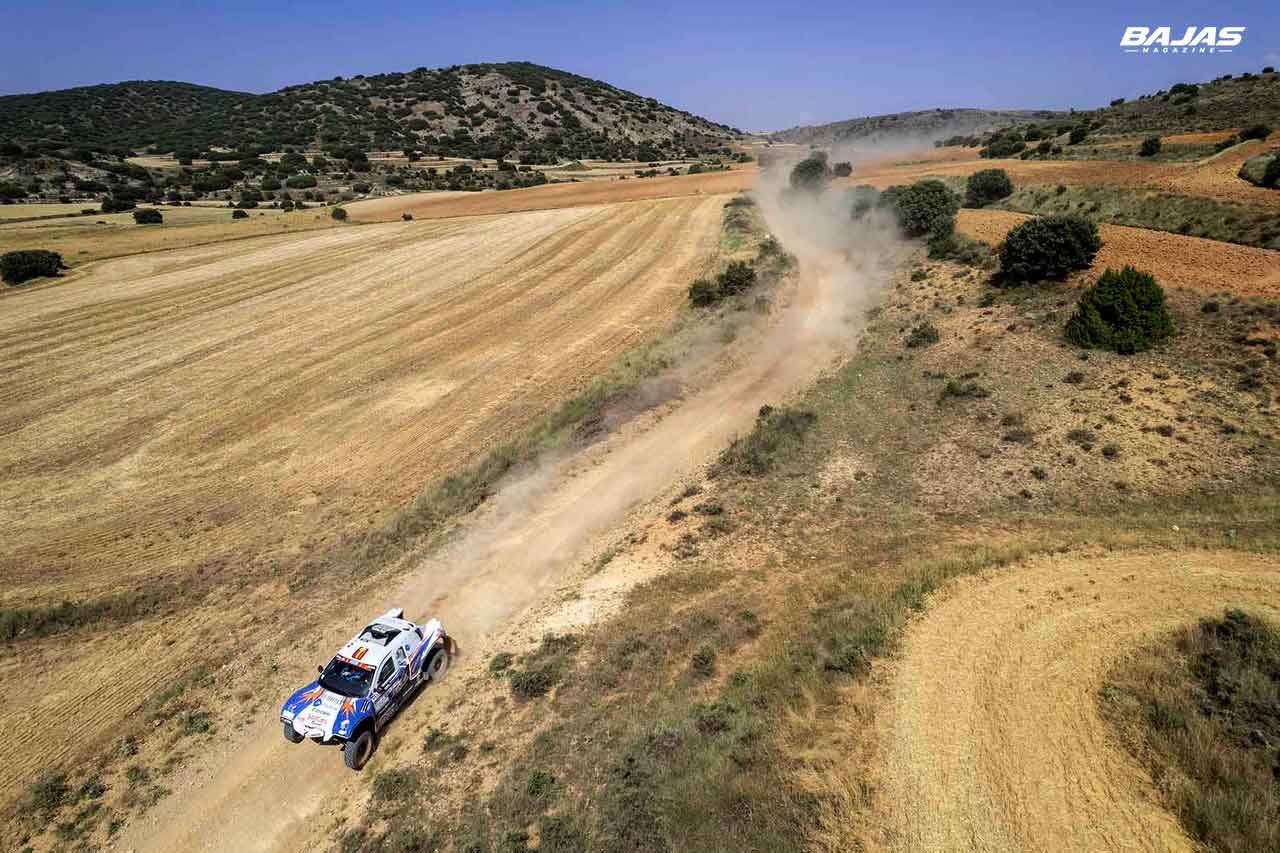 Coche de rally raid visto desde dron levantando polvo en una pista de tierra de la Baja Aragón